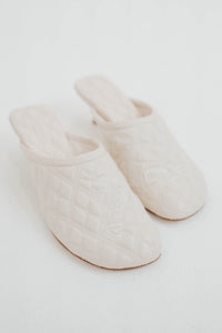 Mules Burberry matelassées en peau d'agneau blanche luxueuse, logo iconique brodé, doublure en peau de mouton, petit talon chaton 2,5 pouces, bout arrondi, semelle cuir, fabrication italienne, design confort raffiné
_vue de face