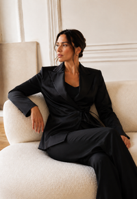 Blouse tuxedo Carolina Herrera en satin noir de la collection Été 2024, style veste croisée avec revers en pointe, nœud latéral à la taille, fermeture boutonnée dissimulée, structure de blazer avec légèreté d'une blouse, fabriquée en Italie
_lifestyle