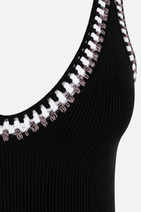 Robe midi Caroline Constas en maille côtelée noire sans manches, broderies artisanales blanches et terre de Sienne au décolleté en V, coupe bodycon ajustée_détail