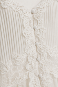 Robe maxi blanche Caroline Constas en chiffon aérien doublé, encolure ornée de dentelle délicate, corsage plissé à taille empire, jupe longue fluide et bretelles ajustables — silhouette bohème chic estivale_détails boutons