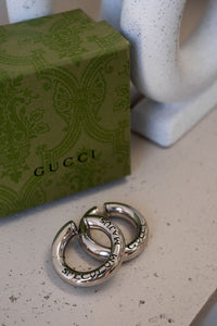 Earcuffs Gucci Speculum Majus en laiton plaqué palladium argenté vieilli, gravures latines et signature GUCCI, système à charnière sans perçage, collection Anger Forest d'Alessandro Michele_closeup