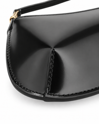 Détail coin et structure sculptée du sac Le Bisou Jacquemus en cuir verni noir, coutures géométriques apparentes, finition miroir laquée, artisanat maroquinier de haute précision, fabriqué en Italie