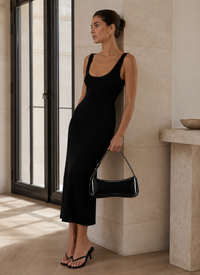 Sac Le Bisou Jacquemus porté à l'épaule, cuir verni noir haute brillance, tombée de sangle 9 pouces, allure hobo bag luxe parisien, look éditorial robe noire, taille unique