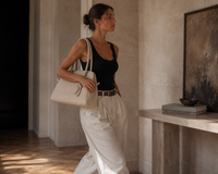 Sac Le Turismo Jacquemus ivoire porté à l'épaule, suède croco embossé blanc cassé, silhouette bowling bag structurée, chute des anses 9.5 pouces, look luxe éditorial, taille unique
