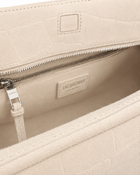 Sac Le Turismo Jacquemus en suède calfskin croco ivoire blanc cassé, logo embossé en relief, format statement bowling bag H9 × L15.5 × P7 pouces, chute des anses 9.5 pouces, taille unique