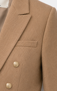 Blazer L'Agence Brooke court en twill coton latté avec fils métallisés dorés, double boutonnage croisé, épaules structurées et boutons blasonnés dorés, style californien luxe_détail tissu
