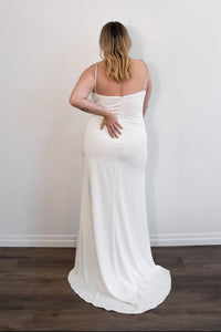 Robe de soirée blanche Mac Duggal ornée de strass argentés, décolleté plongeant en V, bretelles fines serties de cristaux argentés, fente latérale haute bordée de strass, silhouette fluide longue jusqu'au sol_vue de dos