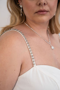 Robe de soirée blanche Mac Duggal ornée de strass argentés, décolleté plongeant en V, bretelles fines serties de cristaux argentés, fente latérale haute bordée de strass, silhouette fluide longue jusqu'au sol_détail strass