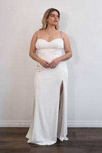 Robe de soirée blanche Mac Duggal ornée de strass argentés, décolleté plongeant en V, bretelles fines serties de cristaux argentés, fente latérale haute bordée de strass, silhouette fluide longue jusqu'au sol_vue de face