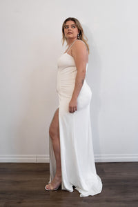 Robe de soirée blanche Mac Duggal ornée de strass argentés, décolleté plongeant en V, bretelles fines serties de cristaux argentés, fente latérale haute bordée de strass, silhouette fluide longue jusqu'au sol_vue latérale