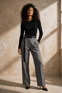 Pantalon Juanita Max Mara en laine grise chinée, taille haute à doubles pinces, ceinture noire à long pan pendant, porté avec un haut noir ajusté, vue éditoriale studio de face - PrettyInsideOut