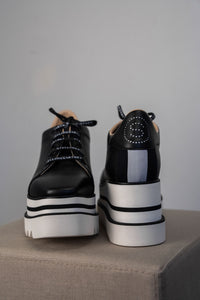 Baskets compensées Stella McCartney Sneak-Elyse en microfibre végane noire, semelle plateforme micro-dentée bicolore noir et blanc, bout carré anguleux, ruban rayé signature au talon, confection italienne_vue de face et de dos