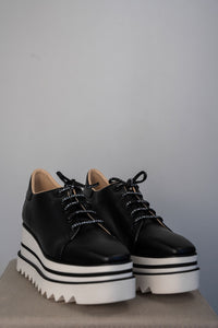 Baskets compensées Stella McCartney Sneak-Elyse en microfibre végane noire, semelle plateforme micro-dentée bicolore noir et blanc, bout carré anguleux, ruban rayé signature au talon, confection italienne_vue complète