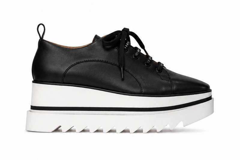 Baskets compensées Stella McCartney Sneak-Elyse en microfibre végane noire, semelle plateforme micro-dentée bicolore noir et blanc, bout carré anguleux, ruban rayé signature au talon, confection italienne_Vue  fond blanc
