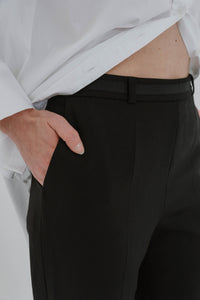 Pantalon The Fold EC1 noir en laine italienne avec devant plat, coupe fuselée cheville et fermeture éclair latérale détail avant 
