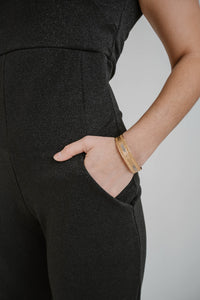 Jumpsuit Chiara Boni La Petite Robe Rebecca en lurex noir métallique avec encolure épaules dénudées et découpes stratégiques détail poche